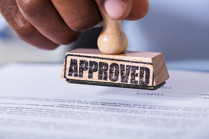 Hand Holding Stamp Over The Document