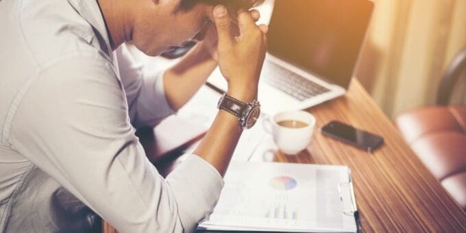 Small Business Cash Flow Management Small Business Cash flow stress, man in front of documents and laptop.